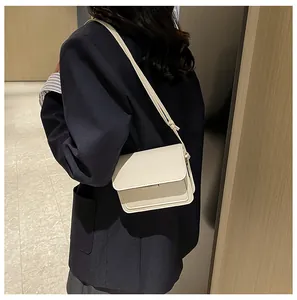 Detailed view of the creamy white leather flap crossbody bag on a navy blazer