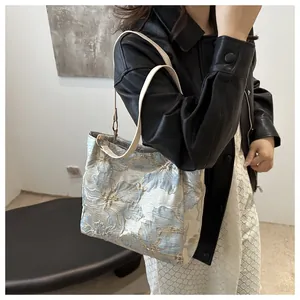 Detailed look at the floral jacquard shoulder bag fabric and thin strap on a model