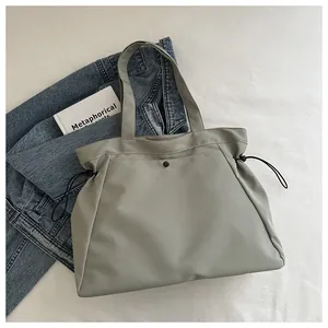 Detail view of sage green tote bag with drawstring and magnetic buckle on fabric background