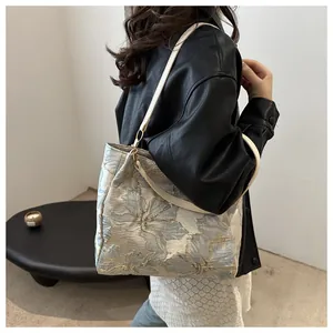 Detail of floral jacquard fabric and white leather strap on a large casual tote bag