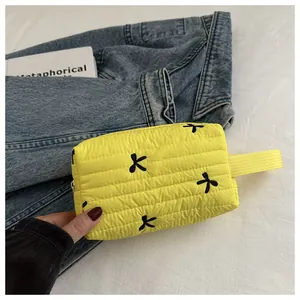 Close-up of yellow quilted vanity bag with black bow embroidery and sturdy webbing handle