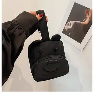 Detalle del bolso de mano negro de nailon con diseño de oso y correa de mano resistente