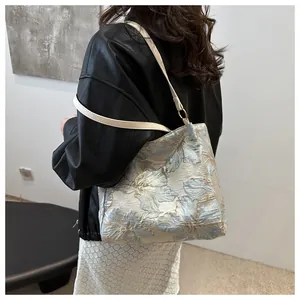 Close-up of floral jacquard tote bag with blue and gold patterns and leather shoulder strap