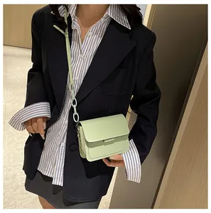 Mint green crossbody bag with chain detail shown on a model for scale and style