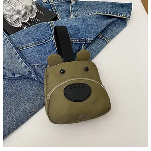 Detalle del mini bolso de lona con forma de oso verde oliva, orejas 3D y asa superior