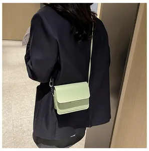 Detailed back view of a mint green leather flap crossbody bag worn with a dark blazer