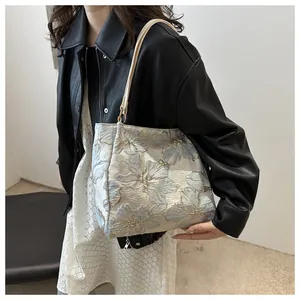 Detail of floral jacquard tote bag with blue and gold butterfly patterns and leather strap