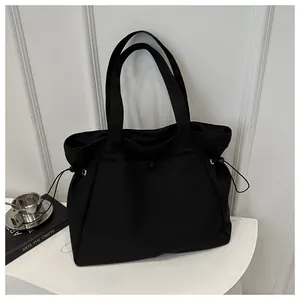 Detail of minimalist black nylon tote bag with functional side adjustable drawstrings