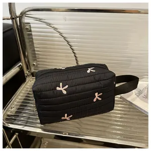 Close-up of black quilted cosmetic bag with pink bow embroidery and fabric handle