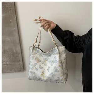 Detailed view of 3D butterfly embroidery and gold metal rings on a beige tote bag