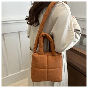 Sac matelassé en nylon caramel porté sur un manteau crème pour un look d'hiver chic