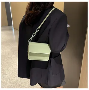 Side view of mint green crossbody bag with chunky resin chain on model in modern setting