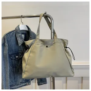 Detail of water-resistant light khaki tote bag with drawstring sides and strap