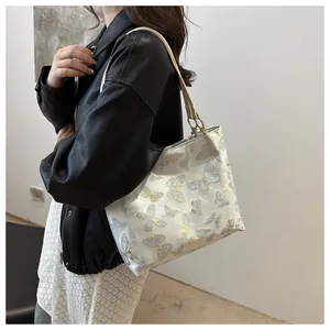 Detailed butterfly embroidery on large white tote bag with light khaki shoulder straps