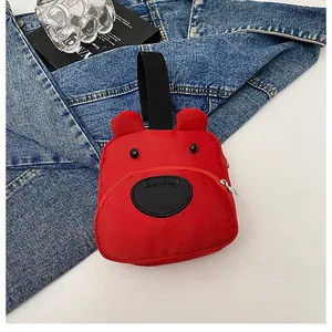 Primer plano del minibolso de oso de lona roja sobre una chaqueta vaquera