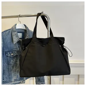 Detail of black large capacity tote bag with drawstring side and snap button closure