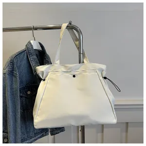 Minimalist white tote bag showing the top drawstring closure and black metal snap detail