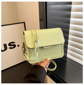 Detail of mint green crossbody bag featuring chunky plastic chain and metal buckle closure