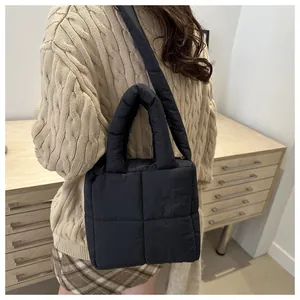 Détail d'un sac cabas matelassé noir avec large bandoulière et texture douce en nylon