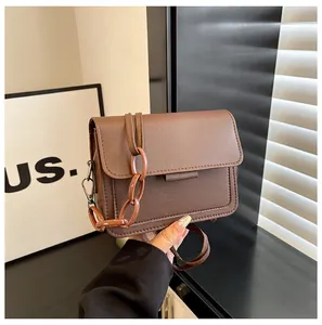 Detail of brown PU leather crossbody bag with adjustable strap and resin chain link