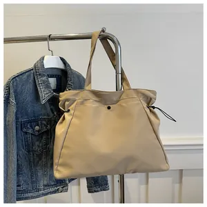 Detail of khaki tote bag showing drawstring sides, snap button and wide shoulder strap