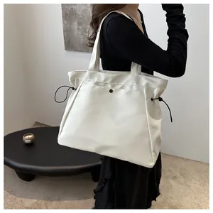 Detail of a large cream tote bag showing the black drawstring and snap button closure