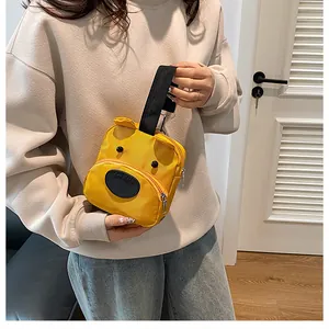 Detalle del bolso bandolera de nailon amarillo con forma de oso y orejas en 3D