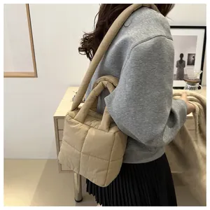 Sac à main matelassé moderne en nylon kaki porté à l'épaule par un mannequin en studio