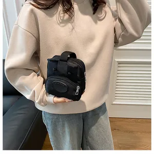 Detalle del mini bolso tote de lona negra con diseño de ojos y bolsillo frontal con cremallera