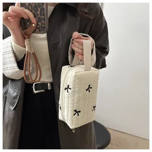Detail of beige quilted makeup bag with black bow embroidery and fabric handle