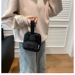 Detalle del diseño de cara de animal y el parche de cuero en el pequeño bolso de lona negro