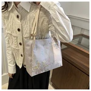 Close-up of lavender satin tote with floral embroidery and gold ring handle detail