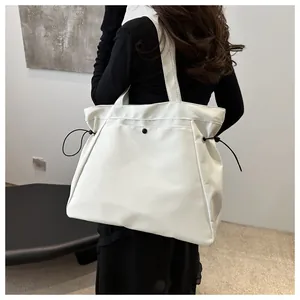 Close-up of white oversized tote bag with black drawstring details and snap closure