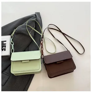 Detail of minimalist rectangular crossbody bags with resin chain strap in green and brown