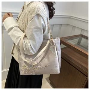Detailed view of floral embroidery on light pink tote bag with gold ring hardware