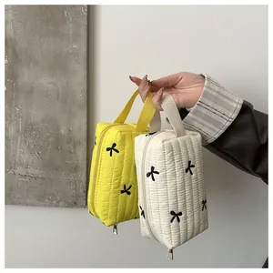 Close-up of quilted makeup bags with black bow embroidery and convenient carrying handles