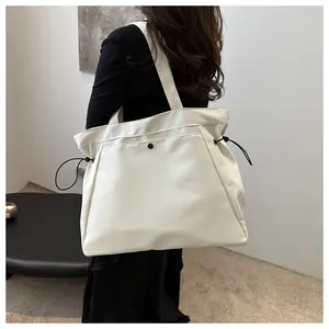 Close-up of a large white tote bag with side drawstrings shown on a fashion model