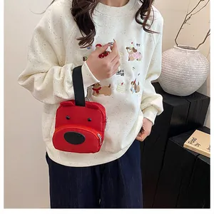 Primer plano de un mini bolso de lona roja con forma de perro llevado por modelo