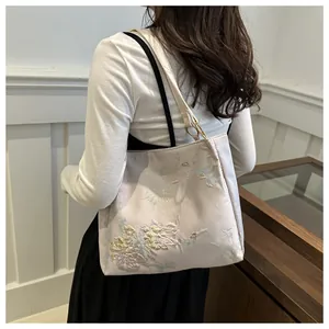 Detail view of pink butterfly floral embroidery on the satin shoulder tote bag