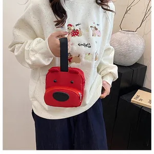 Detalle de bolso rojo de lona con forma de perro y orejas 3D, sostenido para ver tamaño