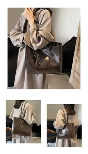 Detail of dark brown wax leather tote bag featuring woven charm and shiny surface