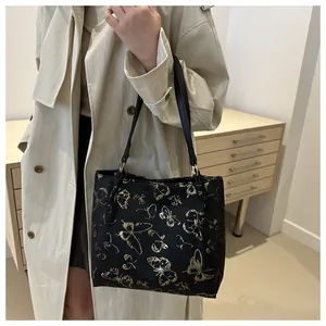 Detail of black tote bag with gold butterfly prints and textured fabric finish