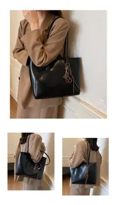 Detail of black faux leather tote bag with elegant metallic charm and sleek straps