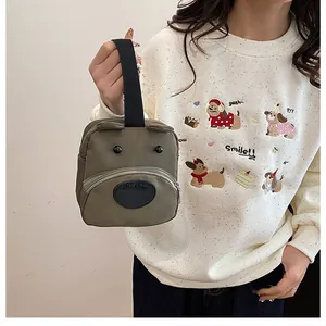 Bolso de lona verde con forma de oso mostrado por una modelo para ver el tamaño