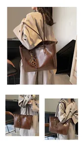 Detail of dark brown leather tote bag showing textured matte finish and pretzel pendant