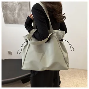 Detail of light green tote bag with side drawstring and smooth nylon texture for daily use