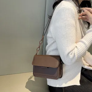 Brown vintage flap square bag with resin chain strap shown on a model with white cardigan
