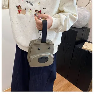 Detalle del bolso de lona caqui con forma de perro, orejas de oso y bolsillo frontal