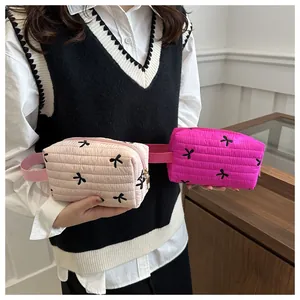 Close-up of quilted pink makeup bags with black bow patterns and side handles