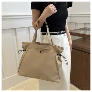 Detail of beige large capacity tote bag with drawstring side and snap button closure